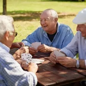 Four elderly men playing cards in a garden